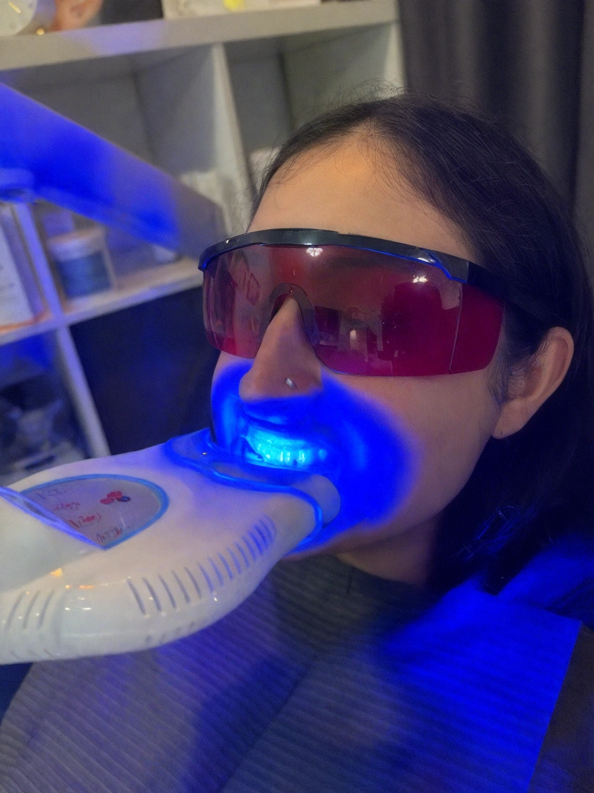 Client receiving a professional LED teeth whitening treatment with protective goggles at Nin's Beauty Salon in Delta, BC